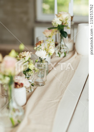 Elegant neutral coloured wedding table scape with flowers and candles 119253762