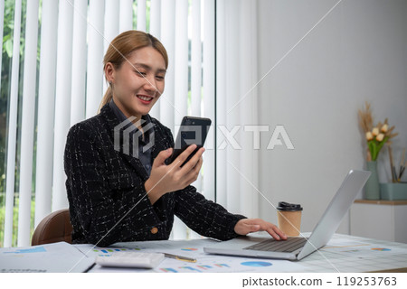 Business Woman Working on Documents at Modern Office Desk with Laptop and Smartphone 119253763