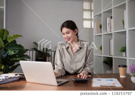Businesswoman Working on Laptop in Modern Office with Plants and Documents on Desk Businesswoman Working on Laptop in Modern Office with Plants and Documents on Desk 119253797
