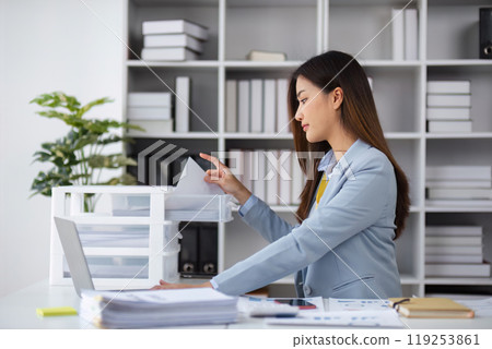 Professional Female Accountant Analyzing Financial Management Documents in Modern Office Setting 119253861