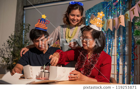 A woman in a red shirt is cutting a cake with a man and a woman watching A woman in a red shirt is cutting a cake with a man and a woman watching 119253871