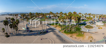 Aerial view of Venice Beach in Los Angeles, featuring sandy shores, tall palm trees, colorful buildings, and a clear blue sky in a sunny setting. 119254074