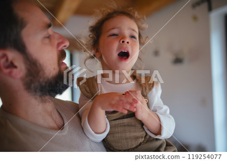 Sick girl with fever and cold at home. Father holding crying daughter. 119254077