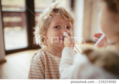 Boy with stuffy nose, using nasal suction bulb to clear mucus from his nose. Boy with stuffy nose, using nasal suction bulb to clear mucus from his nose. 119254080
