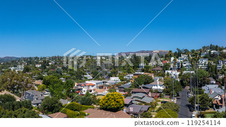 An aerial view captures a residential area in Hollywood, Los Angeles, with diverse homes and lush greenery. The Hollywood Hills are visible in the background. An aerial view captures a residential area in Hollywood, Los Angeles, with diverse homes and lush greenery. The Hollywood Hills are visible in the background. 119254114