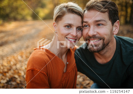 Couple in love on a walk in autumn forest. Husband and wife standing in the middle of forest, touching with foreheads. Couple in love on a walk in autumn forest. Husband and wife standing in the middle of forest, touching with foreheads. 119254147