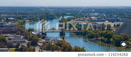 Aerial perspective of Sacramento, California, highlighting the yellow gold Tower Bridge over the Sacramento River, with urban and natural landscapes. Aerial perspective of Sacramento, California, highlighting the yellow gold Tower Bridge over the Sacramento River, with urban and natural landscapes. 119254268