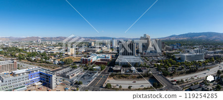 Reno, Nevada's urban landscape is seen from above, featuring high rise casino hotels, residential areas, and distant mountains under a clear blue sky. Reno, Nevada's urban landscape is seen from above, featuring high rise casino hotels, residential areas, and distant mountains under a clear blue sky. 119254285