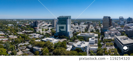 Aerial view of Sacramento, California, featuring a glass skyscraper, the California State Capitol with its white dome, and surrounding greenery. Aerial view of Sacramento, California, featuring a glass skyscraper, the California State Capitol with its white dome, and surrounding greenery. 119254320