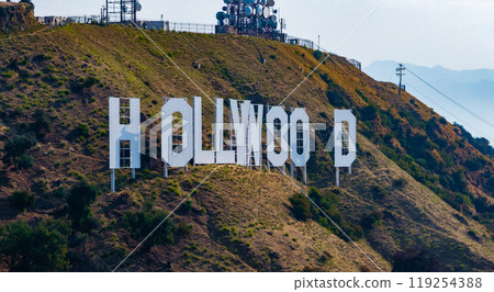 The Hollywood Sign reads 'OLLYWOO' with missing letters, set against rugged hills and sparse vegetation. Communication towers are visible in the background. The Hollywood Sign reads 'OLLYWOO' with missing letters, set against rugged hills and sparse vegetation. Communication towers are visible in the background. 119254388