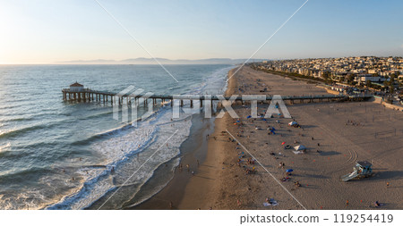 Aerial perspective of Manhattan Beach, California, with the pier extending into the Pacific Ocean, sandy shores, and a backdrop of residential buildings. 119254419