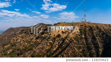 The Hollywood Sign stands prominently on Los Angeles hills, with a communication tower nearby. Partly cloudy skies enhance the rugged terrain backdrop. The Hollywood Sign stands prominently on Los Angeles hills, with a communication tower nearby. Partly cloudy skies enhance the rugged terrain backdrop. 119254423