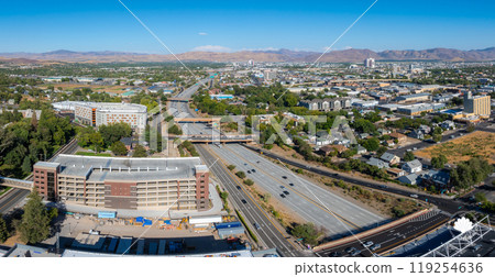 Aerial view of Reno, Nevada, featuring urban landscape, highways, and Sierra Nevada mountains under clear skies and bright daylight. 119254636