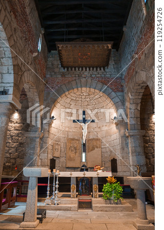 Explore the serene atmosphere of a historic Sardinian church, featuring Romanesque architecture, a prominent crucifix, and elegant stone arches. 119254726