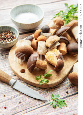 A colorful assortment of fresh mushrooms on a wooden cutting board with herbs and spices A colorful assortment of fresh mushrooms on a wooden cutting board with herbs and spices 119255207