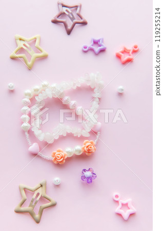 Colorful beads and charms arranged creatively on a pink background for a playful crafting session Colorful beads and charms arranged creatively on a pink background for a playful crafting session 119255214