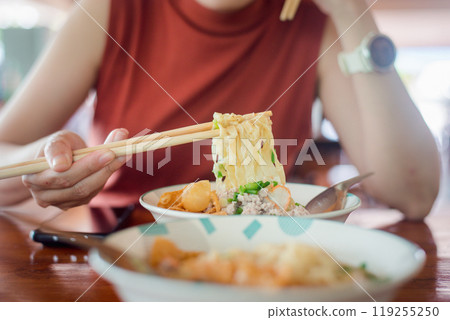 Woman hands holding delicious egg noodle with chopsticks Woman hands holding delicious egg noodle with chopsticks 119255250