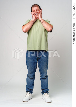 Happy middle-aged man showing joy while touching his face against a neutral background Happy middle-aged man showing joy while touching his face against a neutral background 119255656