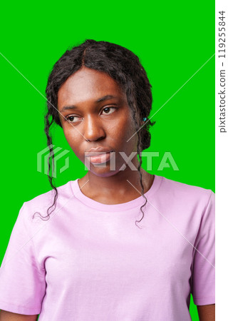 Young woman with an expression of contemplation poses against a bright green background Young woman with an expression of contemplation poses against a bright green background 119255844