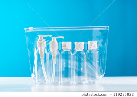 Transparent toiletry bag containing various travel-sized containers on a bright blue background Transparent toiletry bag containing various travel-sized containers on a bright blue background 119255928