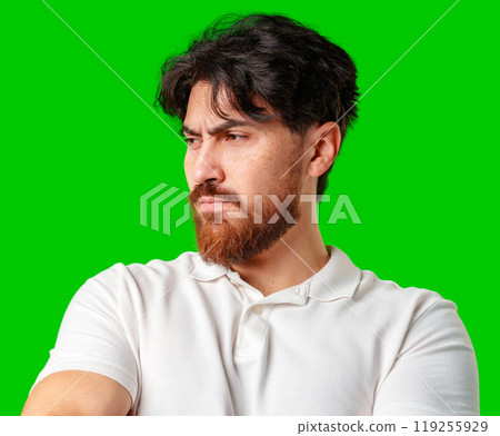 A man with a serious expression stands with crossed arms against a vibrant green background A man with a serious expression stands with crossed arms against a vibrant green background 119255929