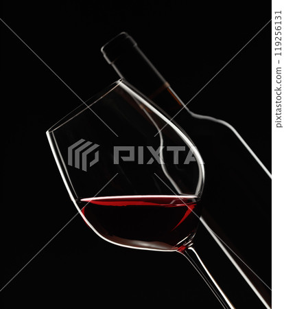 Glass and bottle of red wine on a black background. 119256131