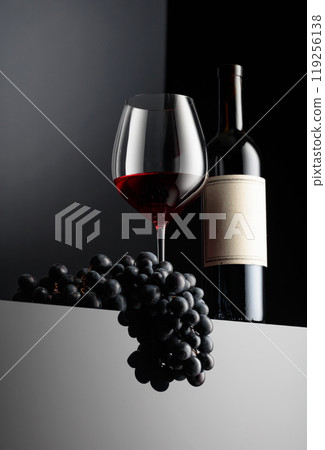 Red wine and blue grapes on a dark background. 119256138