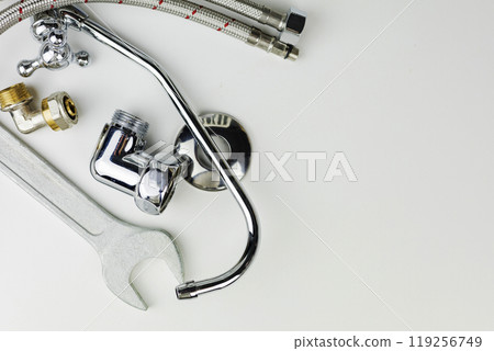 A wrench is currently laying on a pristine white surface adjacent to a faucet A wrench is currently laying on a pristine white surface adjacent to a faucet 119256749