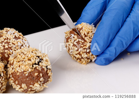 Beautiful candies with sesame seeds on a white plate on a black background 119256888