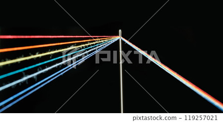 multi-colored threads for sewing in the form of a rainbow pass through an antique needle on a black background 119257021