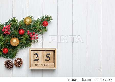 christmas tree branch with toys and gifts and wooden calendar december 25 on wooden background 119257037