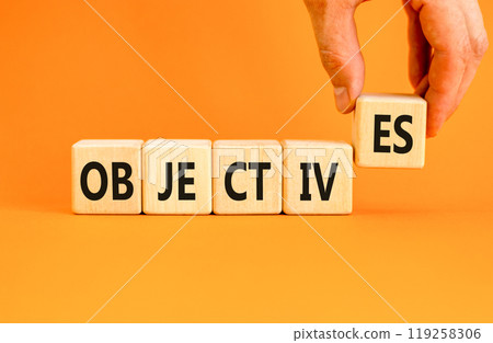 Objectives symbol. Concept word Objectives on beautiful wooden blocks. Beautiful orange background. Businessman hand. Business objectives concept. Copy space. Objectives symbol. Concept word Objectives on beautiful wooden blocks. Beautiful orange background. Businessman hand. Business objectives concept. Copy space. 119258306