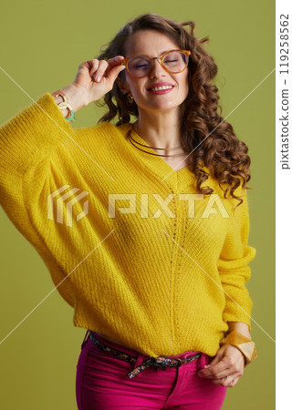 smiling woman in sweater and glasses isolated on green 119258562