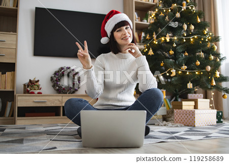 Young woman with Santa hat celebrating Christmas at home Young woman with Santa hat celebrating Christmas at home 119258689