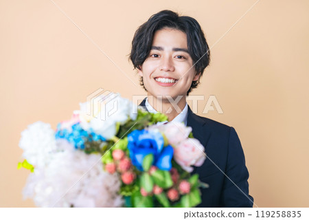 一個穿著西裝的男人拿著一束鮮花 119258835
