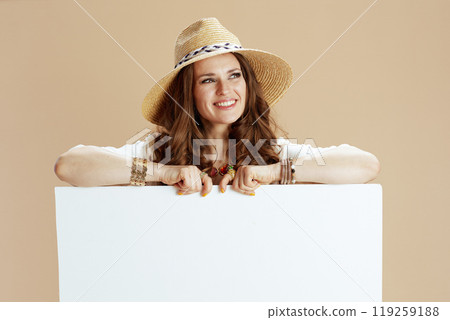 smiling elegant woman showing blank board isolated on beige 119259188