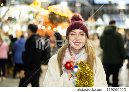 Young woman has purchased decorations for Christmas tree, tinsel and colorful balls 119260035