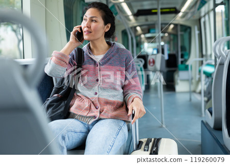 Oriental woman talking on mobile phone while riding a tram 119260079