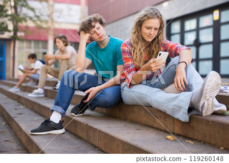 Teenagers sitting on stairs near school 119260148