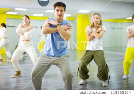 Confident sporty teenage dancers performing energetic dancing movements in modern studio with mirrors 119260164