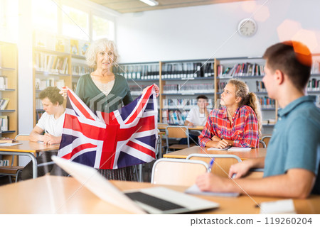 Mature female teacher shows scholchildren the national flag of Great Britain 119260204