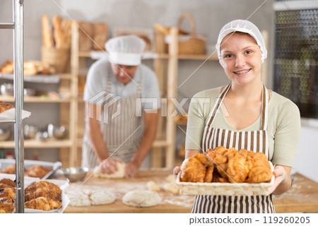 Young woman baker with basket of croissants 119260205