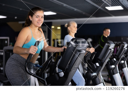 Fitness woman in sportswear doing cardio training on ellipsoid in gym 119260276