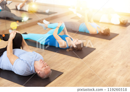 Elderly man doing glutes stretching exercises at training in gym 119260318