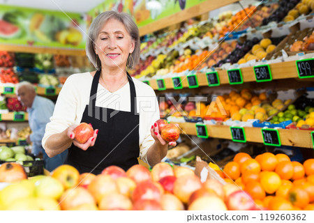 Woman merchandiser in apron putting goods on shelf in supermarket 119260362