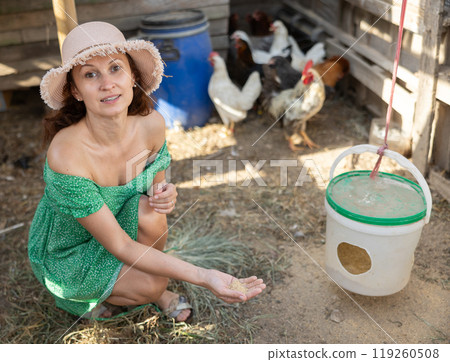 Adult woman feeding chickens in henhouse 119260508