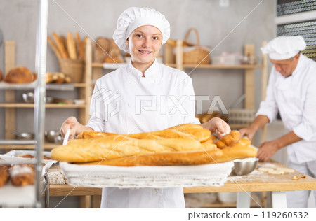 Young woman baker with basket of baguettes Young woman baker with basket of baguettes 119260532