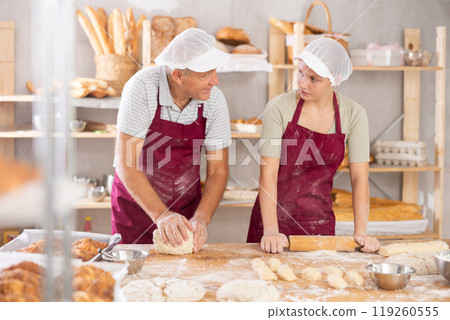 Pensioner man and girl make dough, employee kneads lump of dough, assistant works with rolling pin 119260555