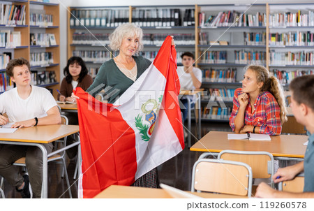 Mature female teacher shows scholchildren the national flag of Peru Mature female teacher shows scholchildren the national flag of Peru 119260578