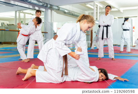 Teenager girls practicing karate in pairs Teenager girls practicing karate in pairs 119260598